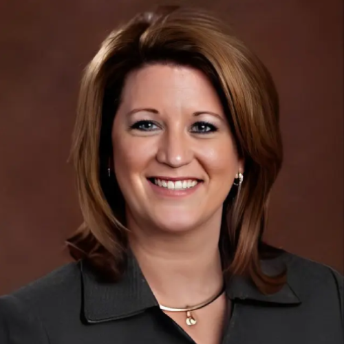 Professional woman with shoulder-length hair smiling against a brown background.