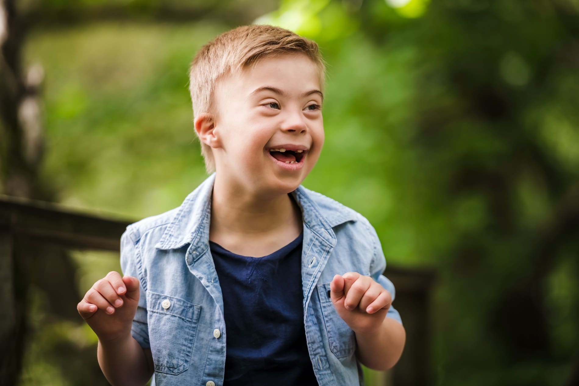 Happy boy with Down syndrome smiling outdoors.