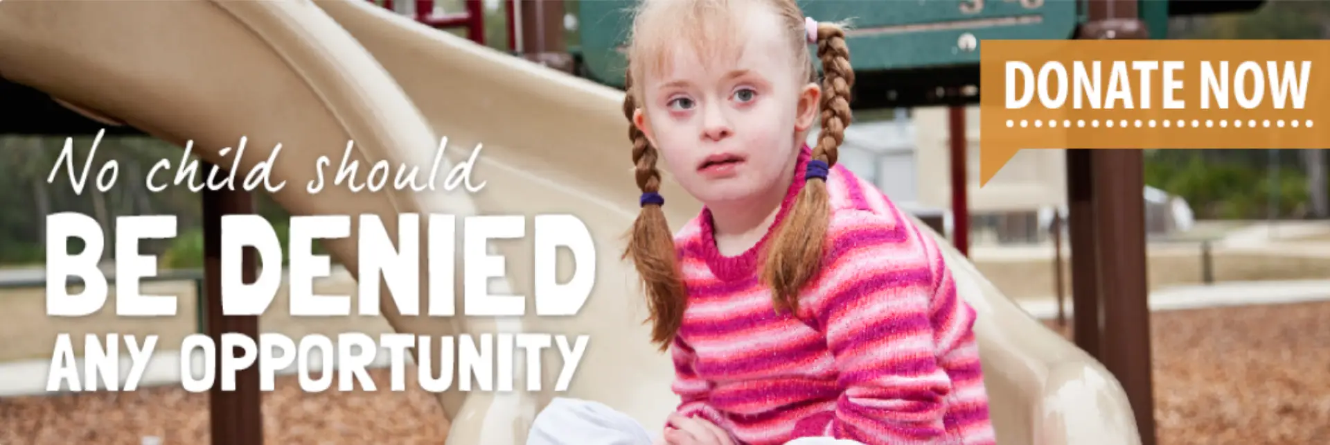 Young girl with Down syndrome in a pink striped sweater and pigtails.