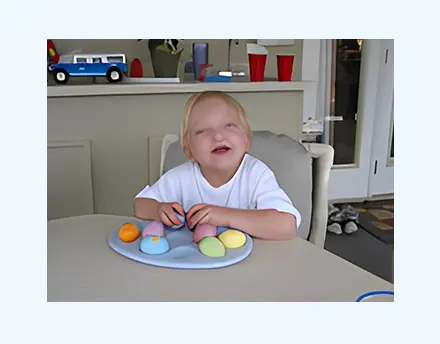 A happy child sitting at a table with colorful macaron cookies.