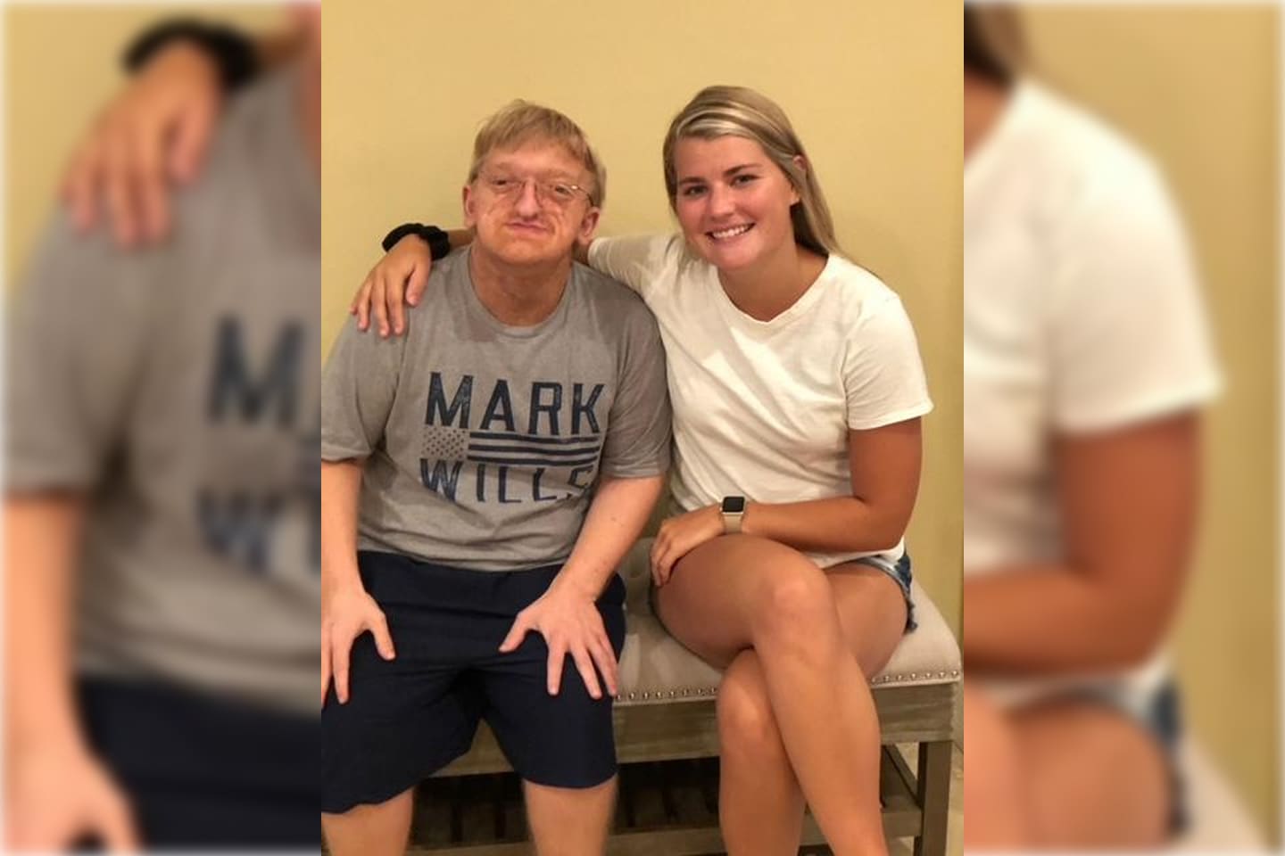 Two people sitting closely, smiling at the camera indoors.