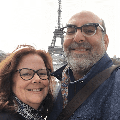 Couple smiling with the Eiffel Tower in the background.